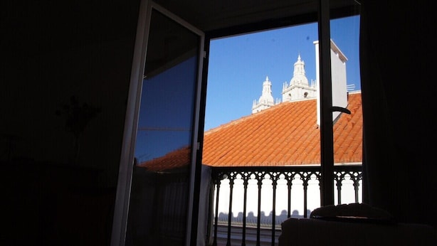 A room with a large window overlooking a building with a red roof and white walls.