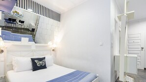 Hotellihuone, jossa on sänky, peili, työpöytä tuoleineen sekä kylpyhuone, jossa on suihku.