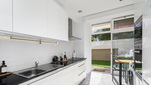 A modern kitchen with white cabinets, a black countertop, and a built-in washing machine. - Suburban Serenity: Family Home with Pool (Algés)
