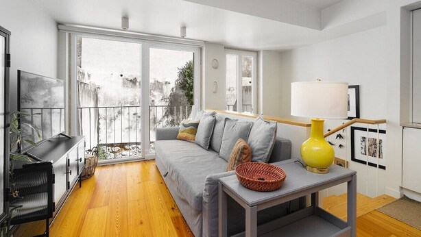 A modern living room with a grey sofa, a yellow lamp, and a TV on a black stand.