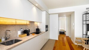 A modern kitchen with white cabinets, a granite countertop, and a wooden floor.
