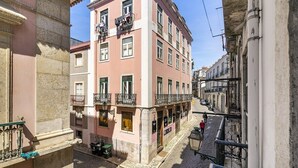 A pink building with balconies and a cobblestone street. - Stylish Family Residence in the Heart of Chiado (Lisboa)