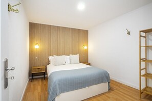 Une chambre à coucher avec une tête de lit en bois, un lit avec une literie blanche, deux tables de chevet et un banc en bois.