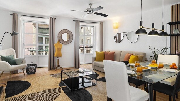 A modern living room with a sofa, coffee table, and dining area. - Stylish Family Residence in the Heart of Chiado (Lisboa)