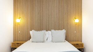 A hotel room with a large bed, two bedside tables, and a wooden headboard with vertical lines. - Stylish Family Residence in the Heart of Chiado (Lisboa)