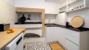 Eine kleine Küche mit weißen Schränken, einer Holz Arbeitsplatte, einem eingebauten Backofen und einem Spülbecken.