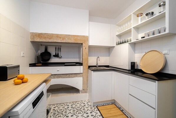 Une cuisine compacte avec des meubles blancs, un plan de travail en bois, un four encastré et un petit évier.