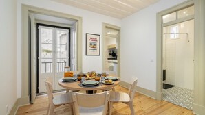 A dining area with a round table set for four, wooden chairs, and a breakfast spread. - Stylish Flat in Downtown Lisbon (Lisboa)