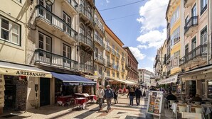 A cobblestone street with shops and outdoor seating, suggesting a pedestrian-friendly area. - Stylish Flat in Downtown Lisbon (Lisboa)