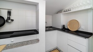 Eine moderne Küche mit weißen Schränken, schwarzen Arbeitsplatten und einem Holzschnittbrett.