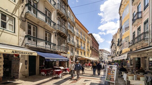 Eine Kopfsteinpflasterstraße mit Geschäften und Außenplätzen, die eine fußgängerfreundliche Umgebung andeutet.