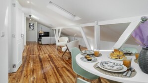 Zona pranzo con pavimento in legno, pareti bianche e tavolo apparecchiato per la colazione.