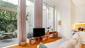 Un salon moderne avec un téléviseur, des meubles en bois et de grandes fenêtres.