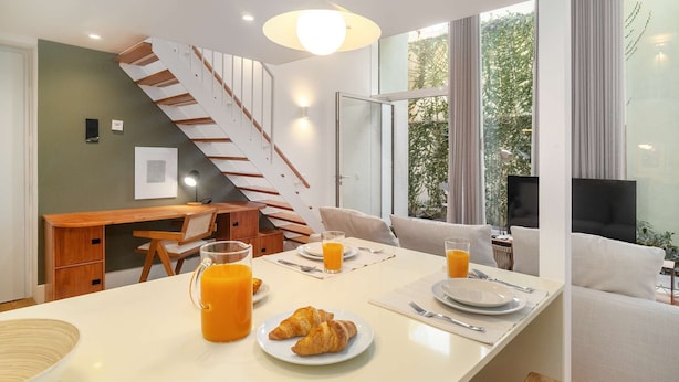 Une cuisine moderne avec un coin repas, un escalier et une grande fenêtre donnant sur un paysage verdoyant.