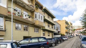 A multi-story residential building with balconies, parked cars, and a clear sky. - Peaceful Algés Family Home away from City Noise (Algés)