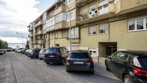 A row of parked cars along a street adjacent to a multi-story building with balconies. - Peaceful Algés Family Home away from City Noise (Algés)