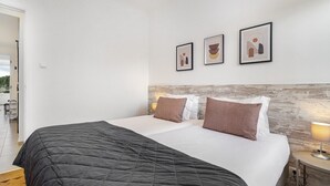 A modern hotel room with a large bed, a wooden headboard, and three framed artworks on the wall. - Peaceful Algés Family Home away from City Noise (Algés)