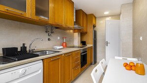 A modern kitchen with wooden cabinets, a dishwasher, a stove, and a sink. - Peaceful Algés Family Home away from City Noise (Algés)