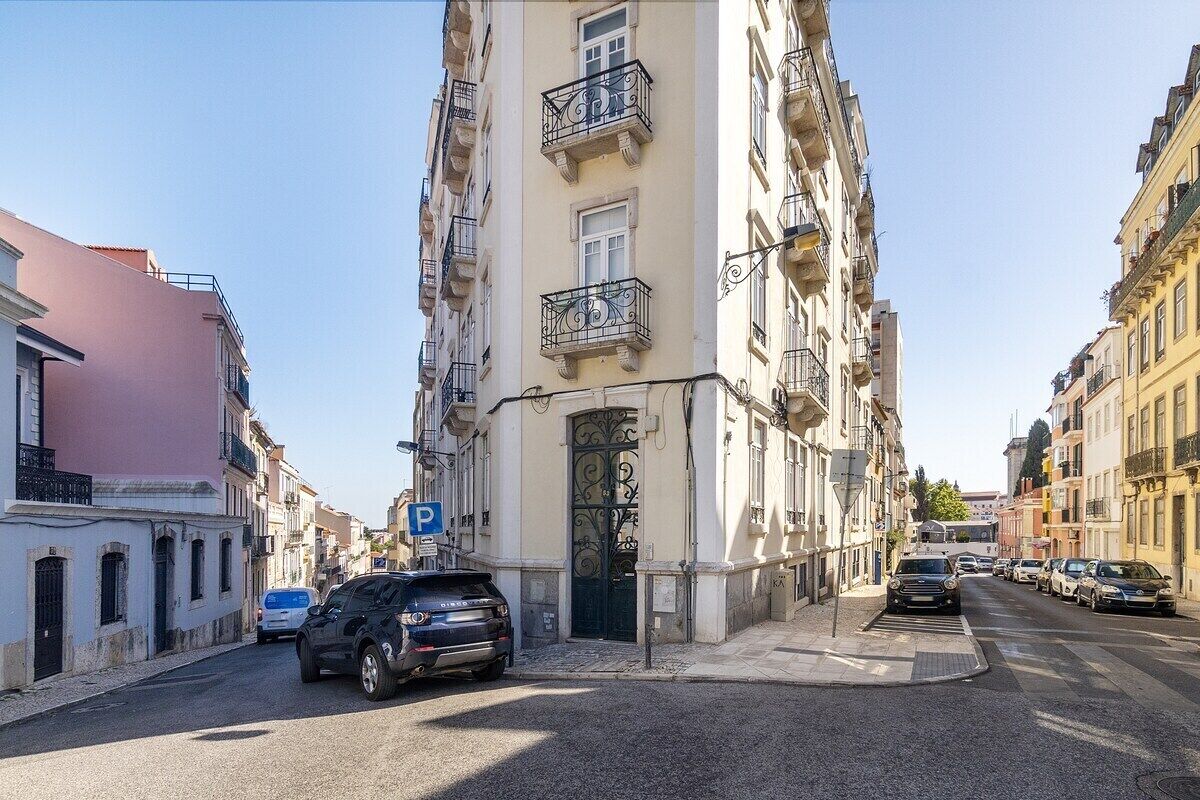 Vista da rua com um edifício com um portão preto imponente e varandas.