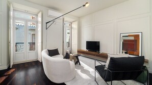 A modern living room with a sofa, armchair, and a TV.
