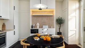 A modern kitchen with white cabinetry, a round dining table, and a pendant light.