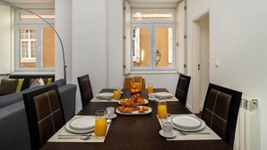 A dining area with a table set for breakfast, including croissants and orange juice.