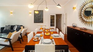 Un coin repas avec une table en bois mise pour le petit-déjeuner, entourée de chaises.