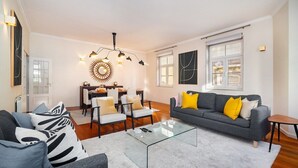 Un salon moderne avec un canapé gris, une table basse en verre et un coin repas agrémenté d’un luminaire au design éblouissant.