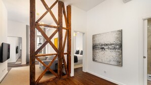 A modern interior with a wooden beam structure, a large abstract painting, and a white wall.