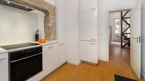 Een moderne keuken met witte kasten, een zwarte oven en een accentmuur van steen.