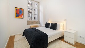 Een moderne slaapkamer met een bed, nachtkastjes, een raam en een schilderij aan de muur.