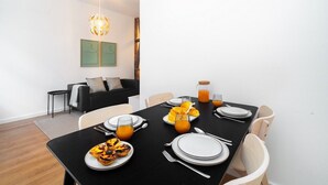 A dining area with a black table set for four, including plates, cutlery, and glasses of orange juice. - Lisbon Living Redefined: Exclusive Downtown Spot (Lisboa)