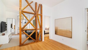 A modern living room with a wooden structure, a large painting, and a TV on a white console. - Lisbon Living Redefined: Exclusive Downtown Spot (Lisboa)