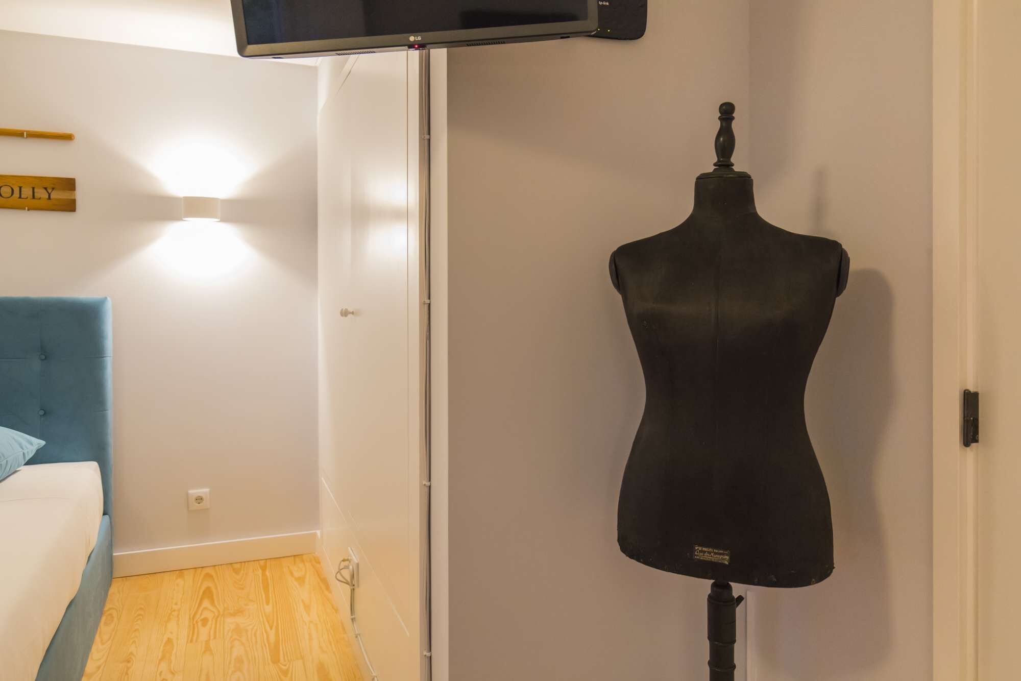 A room with a blue chair, a white wardrobe, and a black mannequin.