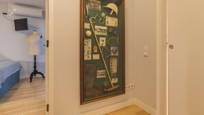 A room with a large framed collage on the wall, a mannequin, and a bed with a blue cover. - Polo Room - Clean & Safe (Lisboa)