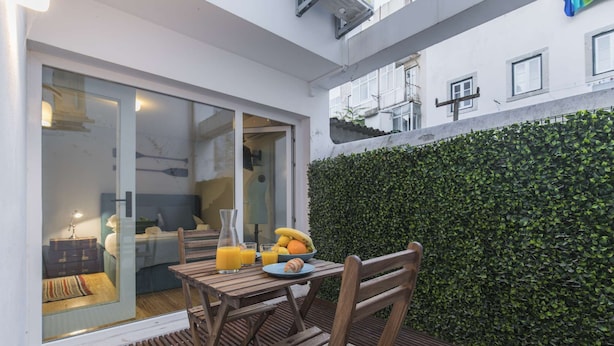 A wooden table with breakfast items, a glass of orange juice, and a bowl of fruit. - Polo Room - Clean & Safe (Lisboa)