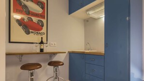 A kitchen with blue cabinets, a white countertop, and two stools. - Polo Room - Clean & Safe (Lisboa)