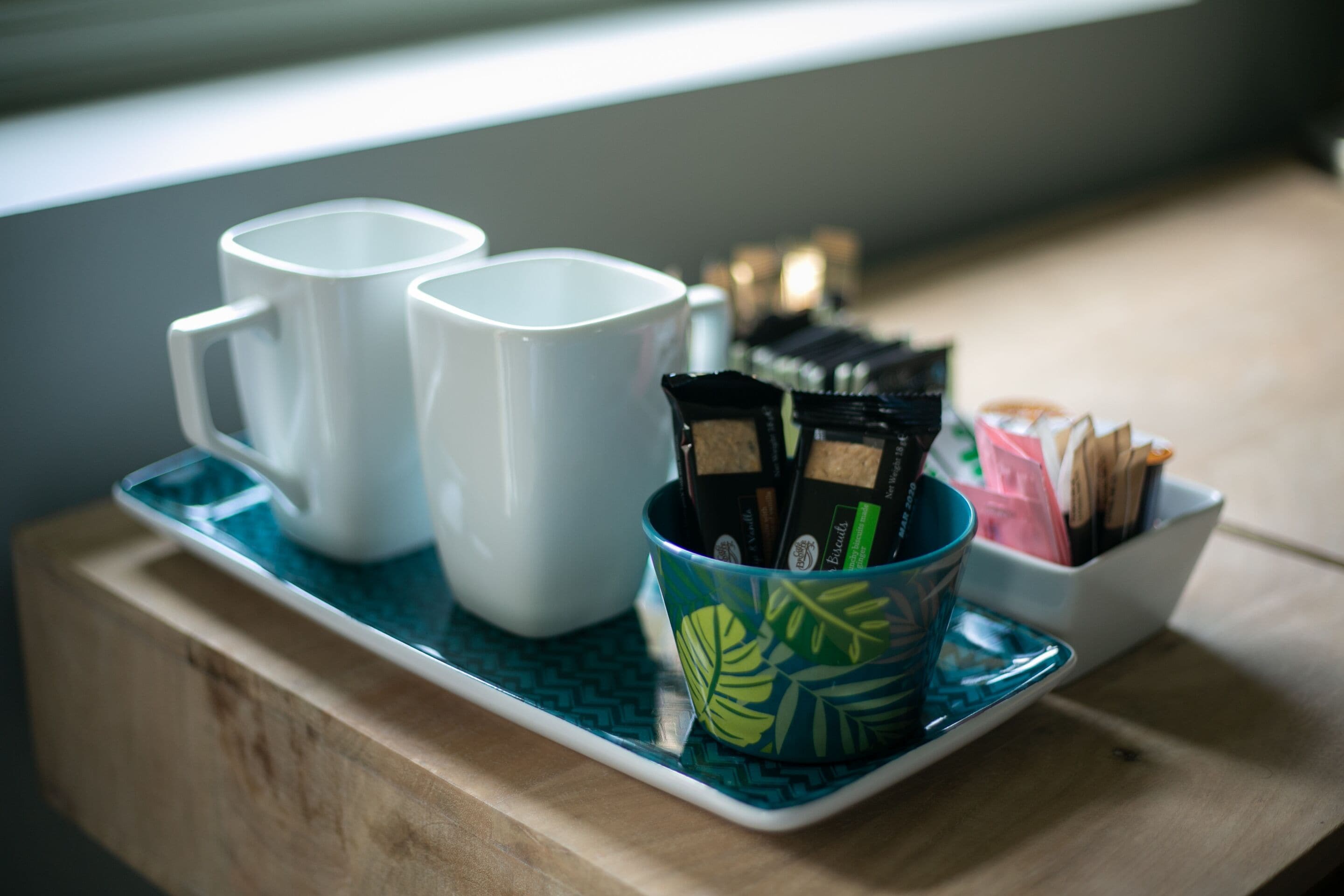 A tray with two white mugs and a colorful mug with tea packets.