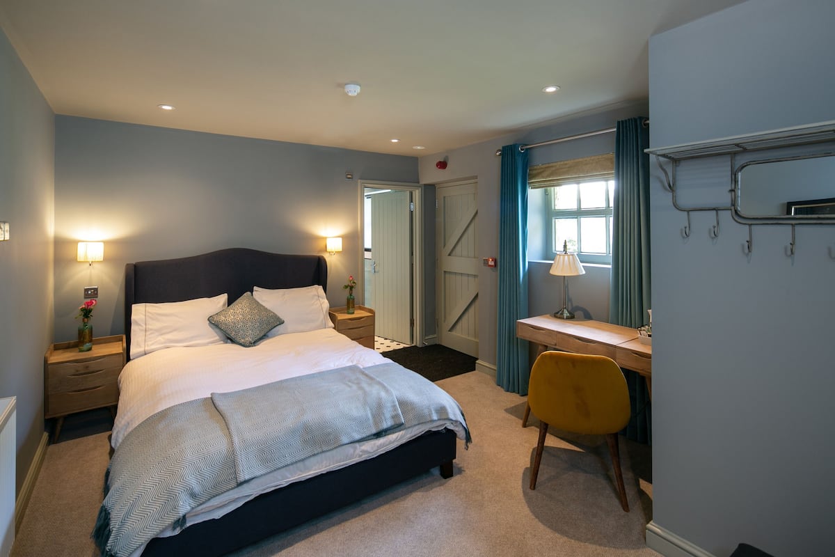 A bedroom with a bed, bedside tables, a desk, and a chair.