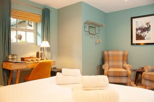 A hotel room with a bed, a desk with a lamp, a chair, and a small table.