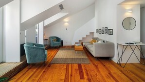 Een moderne woonkamer met een trap, een bank, een fauteuil en een salontafel.