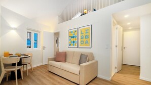Una sala moderna con un sofá color beige, una mesa de comedor con sillas y dos cuadros en la pared.