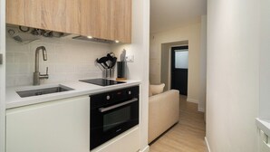 A modern kitchen with white cabinetry, a double sink, a built-in oven, and a light-colored countertop. - Explore Lisbon from a Cozy Base in Alfama (Lisboa)