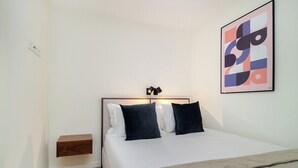 A modern bedroom with a bed, bedside table, and a wall-mounted artwork. - Explore Lisbon from a Cozy Base in Alfama (Lisboa)
