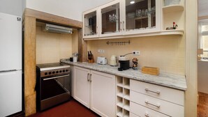 A compact kitchen with white cabinets, a built-in oven, and a marble countertop.