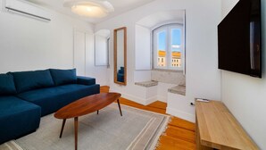 Ein modernes Wohnzimmer mit einem blauen Sofa, einem Holztisch und einem großen Spiegel.