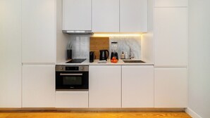 Eine moderne Küche mit weißen Schränken, einem Einbauofen, einer Kaffeemaschine und einer Marmor-Spritzschutzwand.