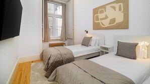 Ein Schlafzimmer mit zwei Betten, einem Fenster, einem Wandbild und einem Fernseher.