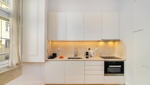 Eine moderne Küche mit weißen Schränken, einem eingebauten Backofen und einem Fenster mit Blick auf Gebäude.