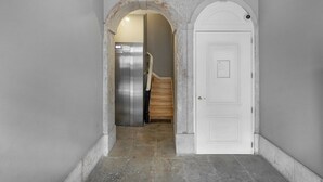 Ein Flur mit einer weißen Tür und einem Edelstahlkühlschrank im Hintergrund.